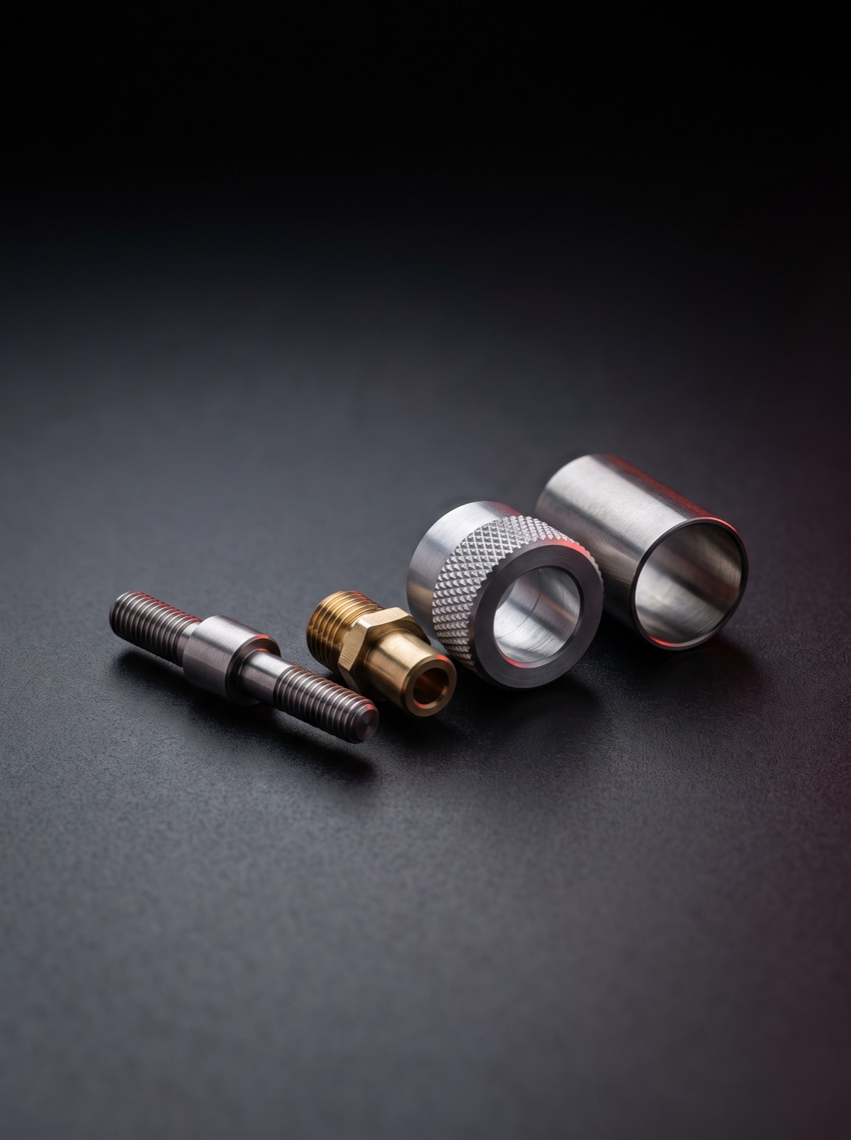 Precision-machined threaded components and fittings on a dark surface