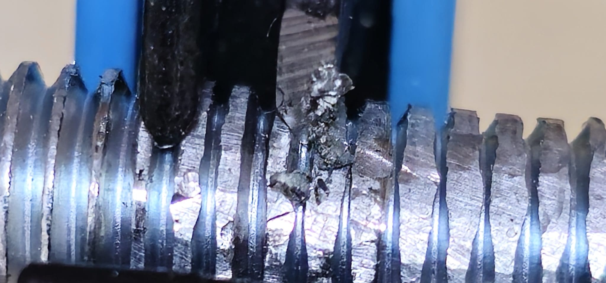 A thread cleaner cutting into and weakening a thread