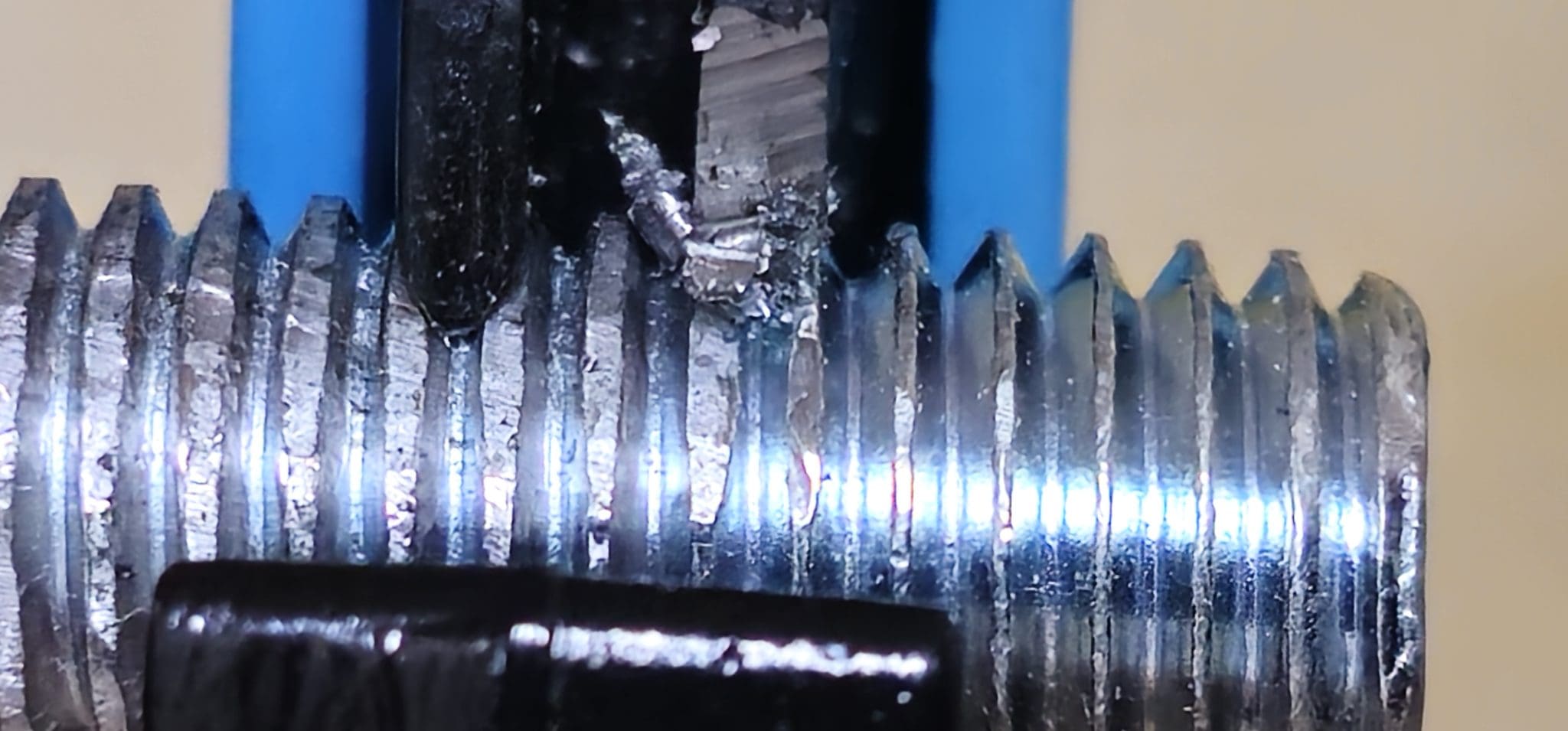 A thread being dressed by a cutting tool, with chips coming off the crest