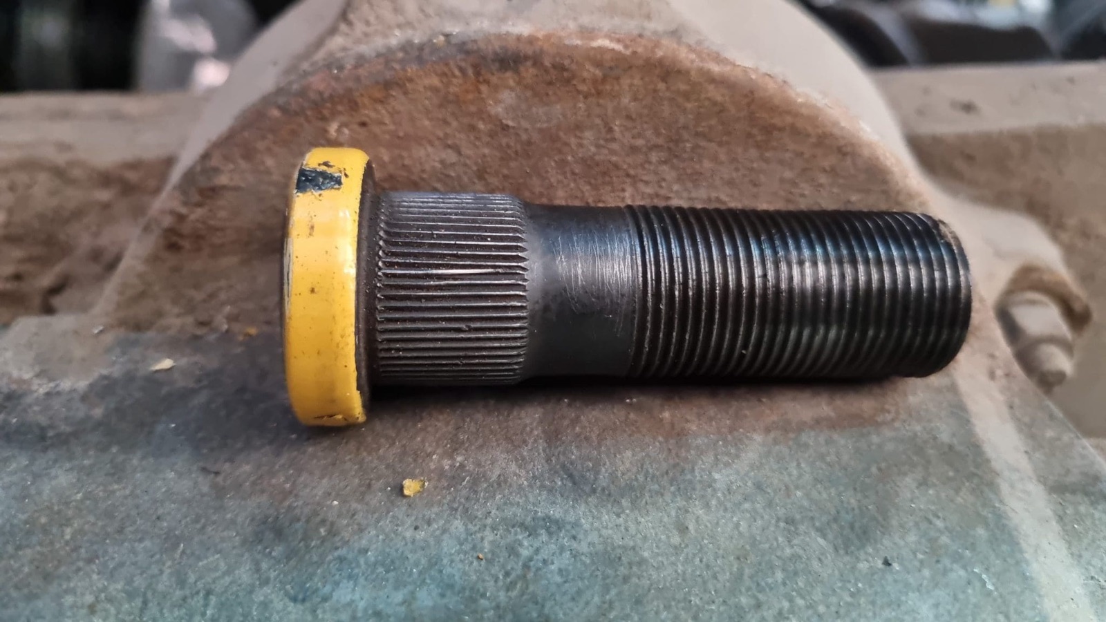 A wheel stud with cleanly restored threads resting on the hub after an X-Nut repair